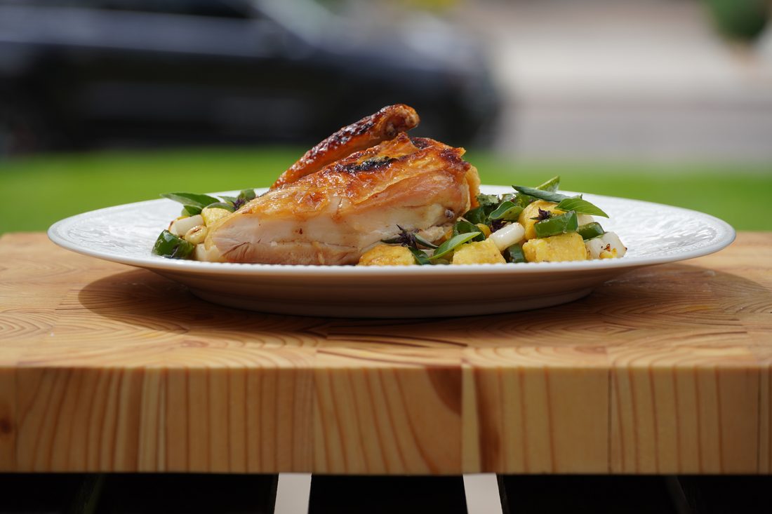 Herb-roasted chicken with charred corn and jalapeño, plated outdoors